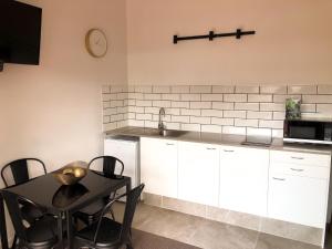 a kitchen with white cabinets and a table with chairs at Orewa Beachcomber in Orewa