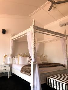 a bedroom with a white canopy bed and a table at Orewa Beachcomber in Orewa