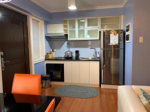 a kitchen with white cabinets and an orange chair at Northpoint Camella Condo Suites in Davao City