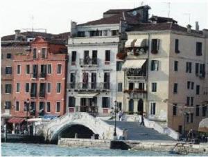 a group of buildings next to a river with a bridge at La Rosa dei Venti in Venice