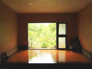 a room with a large window in a room with water at Tengu Onsen Asama Sanso in Komoro