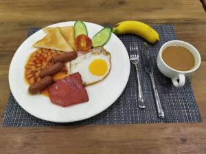 ein Frühstücksteller mit Eiern, Würstchen, Bohnen und einer Tasse Kaffee in der Unterkunft Begonia Resort 薄荷岛海棠度假酒店 in Panglao