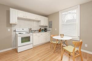 a kitchen with white cabinets and a table with chairs at Sleepover Historic Downtown Springfield Apartments in Springfield