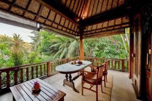 a balcony of a house with a table and chairs at Kebun Indah Ubud in Ubud