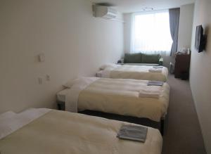 釧路市にあるホテル クラウンヒルズ釧路のベッド4台と窓が備わるホテルルームです。