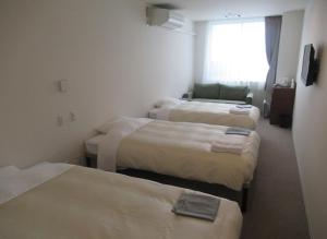a hotel room with three beds and a window at Hotel Crown Hills Kushiro in Kushiro