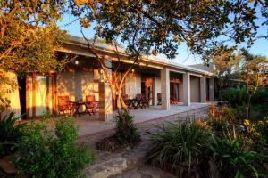 a house with a patio with a table and chairs at Elephants Safari Lodge - Bellevue Forest Reserve in Paterson