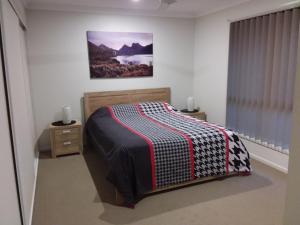 a bedroom with a bed and a picture on the wall at Waratah and Wattle Apartments in Maryborough