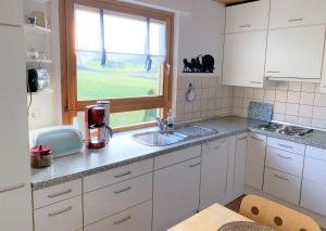 a kitchen with white cabinets and a sink and a window at BodenSEE Apartment Friedrichshafen Manzell in Friedrichshafen