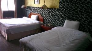 pokój hotelowy z 2 łóżkami i ścianą w obiekcie 雲林東勢御花園汽車旅館 w mieście Dongshi-Yulin 