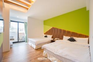 a bedroom with two beds and a green wall at Siao Hai Zih Guest House in Xiaoliuqiu