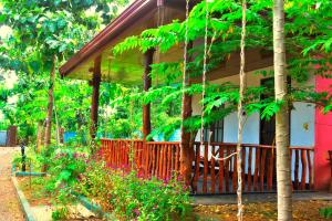 a house with a fence and flowers in front of it at La Casa Safari Cottages & TREE HOUSE in Udawalawe