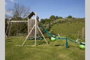 a playground with a swing set in a field at Sherbourne Cottage, Seven Springs Cottages in Cheltenham