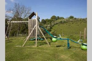 ein Spielplatz mit einer Schaukel auf einem Feld in der Unterkunft Sherbourne Cottage, Seven Springs Cottages in Cheltenham
