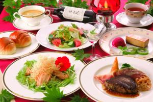 einen Tisch mit Teller mit Speisen und Tassen Wein in der Unterkunft Chuzenji Pension in Nikko