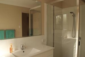 
a bathroom with a shower, sink, and mirror at Banksia and Acacia Apartments in Maryborough

