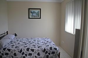 
a bedroom with a white bed and white walls at Banksia and Acacia Apartments in Maryborough
