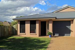 une maison avec un garage et une clôture dans l'établissement Banksia and Acacia Apartments, à Maryborough