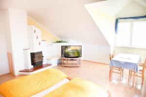 a white living room with a tv and a table at Thermenpension Gigler in Bad Waltersdorf