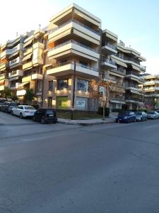duży apartamentowiec z samochodami zaparkowanymi na parkingu w obiekcie Maria’s house w Salonikach