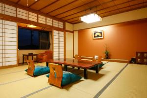 a living room with a wooden table and chairs at Hokuriku Yamashiro Onsen Hotel Kikyou in Yamashiro