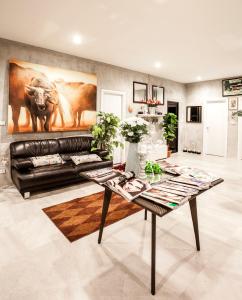 a living room with a black leather couch and a table at White Knot Khao Yai in Ban Khanong Phra Nua