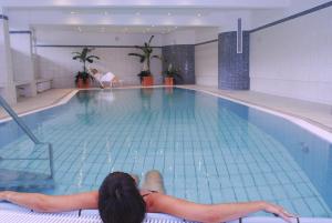 a woman laying on the edge of a swimming pool at Hotel Strandidyll in Grömitz