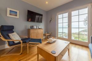The View في Carbis Bay: غرفة معيشة مع طاولة وكراسي ونافذة