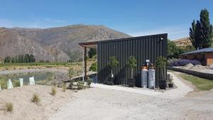 a black shed with two oxygen tanks next to a river at Lodges on Pearson - Unit 2 in Cromwell