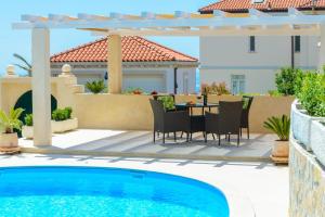 un patio con mesa y sillas junto a una piscina en Villa Ida, en Dubrovnik