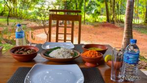 a wooden table with bowls of food and bottles of water at Gal Oruwa Resort in Dambulla