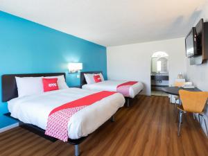 2 letti in una camera con pareti blu e scrivania di OYO Hotel DeRidder Hwy 171 North a DeRidder