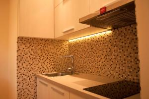 kuchnia ze zlewem i ścianą wyłożoną kafelkami w obiekcie Apartament Turoszowska w Łodzi
