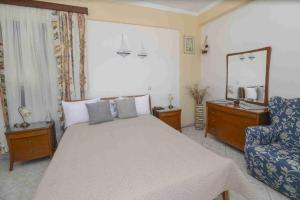 a bedroom with a bed and a chair and a mirror at Yianiskari Holiday House in Vathi