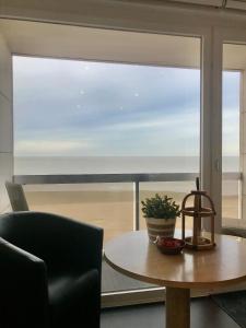 een tafel en stoelen voor een groot raam bij Sea and Dunes in Knokke-Heist