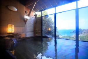 a large swimming pool in a house with a large window at Nishiizu Koyoi in Numazu