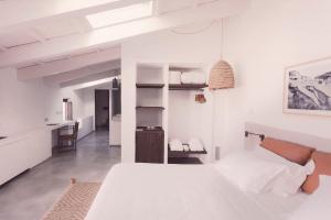 a white bedroom with a large bed and a kitchen at Can Araya in Ciutadella