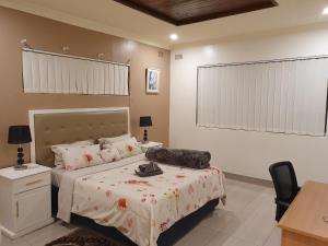1 dormitorio con cama, escritorio y silla en Grey Oak Holiday House en Bulawayo