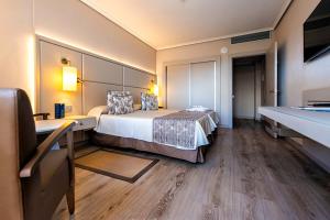 a hotel room with a bed, chair, and nightstand at Spring Arona Gran Hotel - Adults Only in Los Cristianos
