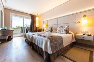 Cette chambre comprend un grand lit et une fenêtre. dans l'établissement Spring Arona Gran Hotel - Adults Only, à Los Cristianos
