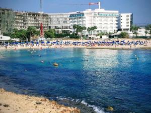 uma praia com um monte de pessoas na água em Christopher's Sandy Beach Suites em Agia Napa