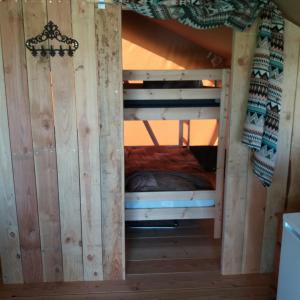 a bunk bed in a tree house with a bed in it at Safaritent de Berghoeve in Ruinen