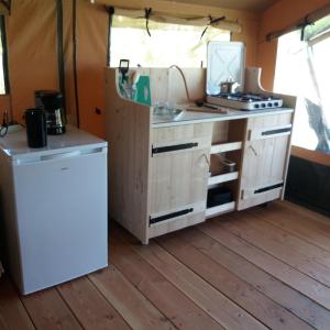 a kitchen in a tent with a stove and a refrigerator at Safaritent de Berghoeve in Ruinen