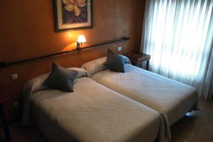 two twin beds in a room with a window at Hotel Lena in Pola de Lena