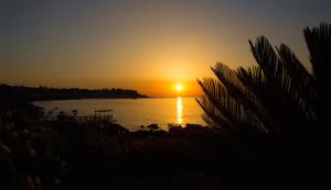 a sunset over a body of water with the sun setting at Appartamento in Villa Agnese in Acitrezza