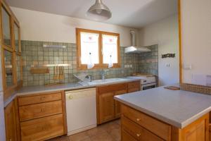 a kitchen with wooden cabinets and a white dishwasher at L'Echaillon - Soldanelle in Névache