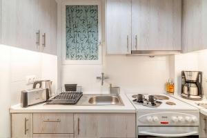 a white kitchen with a sink and a stove at Aegle by Heloni Apartments in Athens