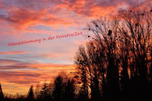 a sunset with trees in front of a cloudy sky at FeWoFreiZeit in Rheinau