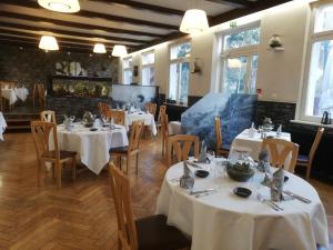 a restaurant with white tables and chairs and windows at Hôtel Restaurant Le Moschenross in Thann