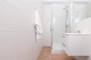 a white bathroom with a shower and a sink at Apartments Gdynia Abrahama in Gdynia